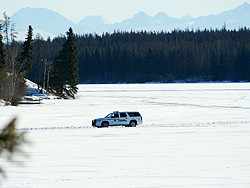 A white RCMP vehicle drives down the lake.