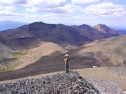 Photo courtesy of Miriam Schilling. A woman stands on a mountain overlooking numerous bare and extinct volcanic peaks.