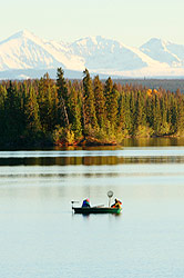 A boat out on Nimpo Lake with autumn colors and white mountains behind.
