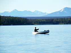 Photo courtesy of Keith Boxer. A man in a silver canoe fly fishing Nimpo Lake.