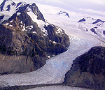 A glacier winds its way around the base of rugged peaks.